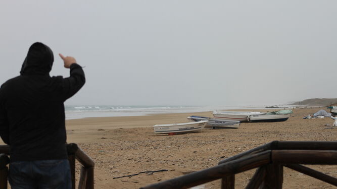 Un hombre situado en una pasarela de acceso a la playa de Zahara de los Atunes señala el lugar desde donde vienen los malos olores en verano.