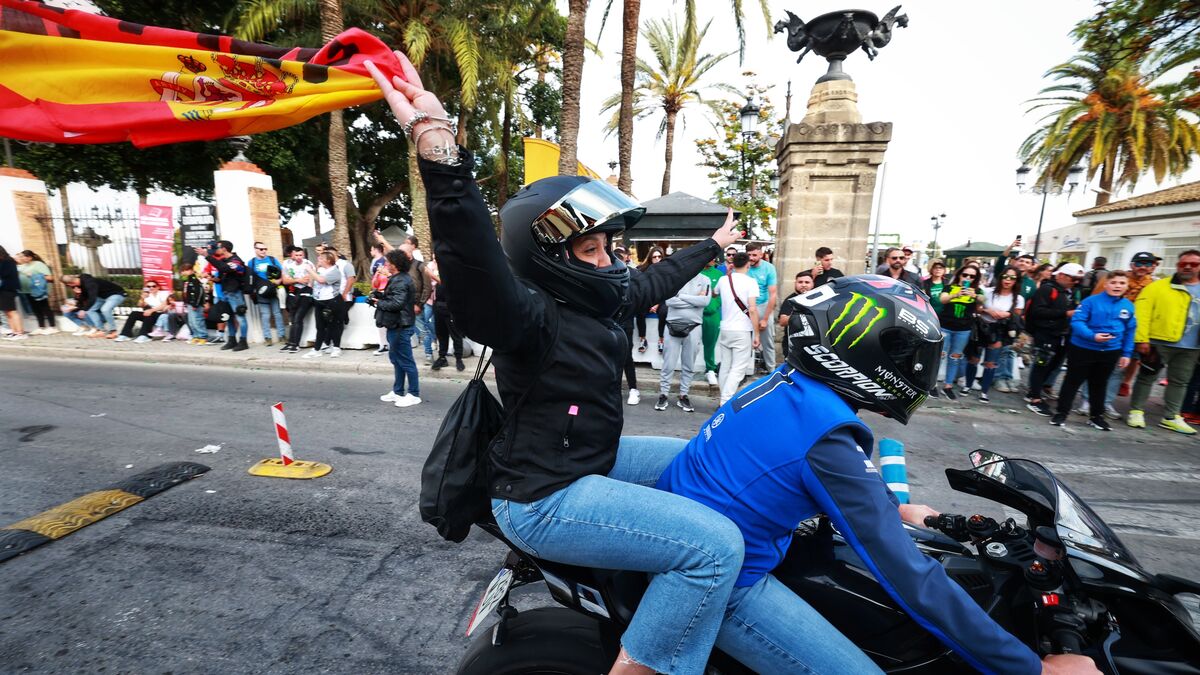 Una aficionada ondea una bandera desde su moto en la Ribera del Marisco.